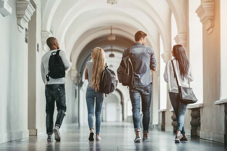 Multiracial students are walking in university hall during break and communicating.