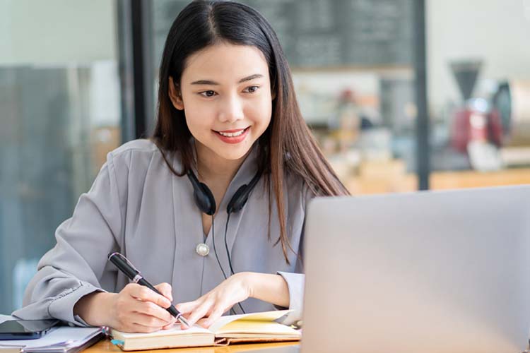 Asian student hang wireless headphones around her neck and learning online.