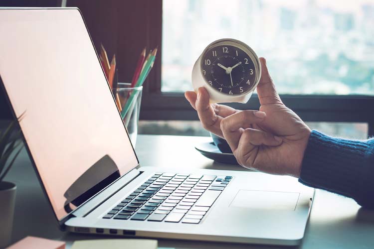 A businessman checks the time in front of a computer laptop.