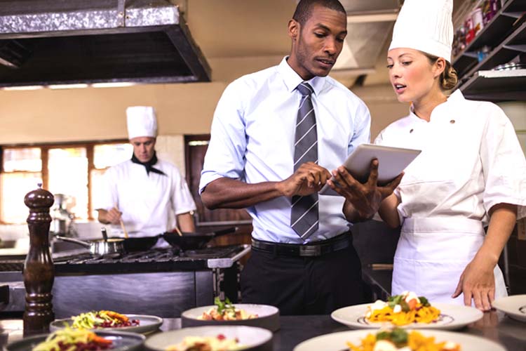 Male manager and female chef using a digital tablet in kitchen.