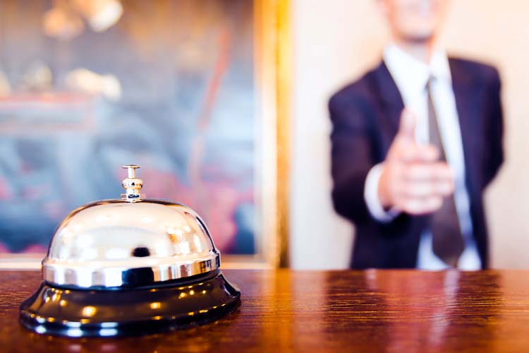 Hotel reception bell and receptionist greeting handshake.