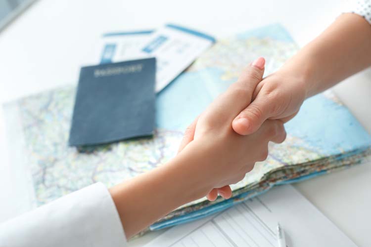 Young female travel agency consultant shaking hands with the client.