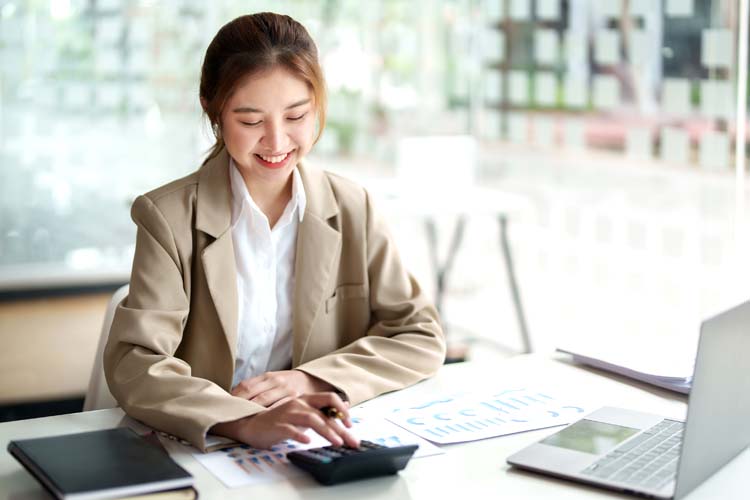 Asian female accountant using a calculator to calculate.