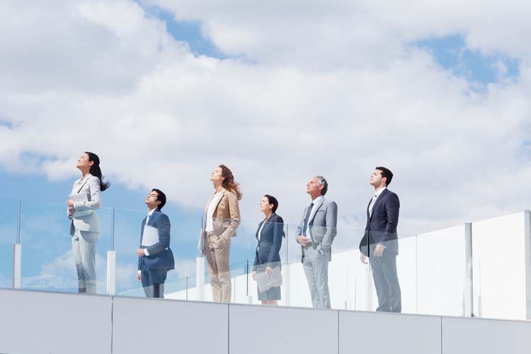 Business people on rooftop balcony looking up at sky.