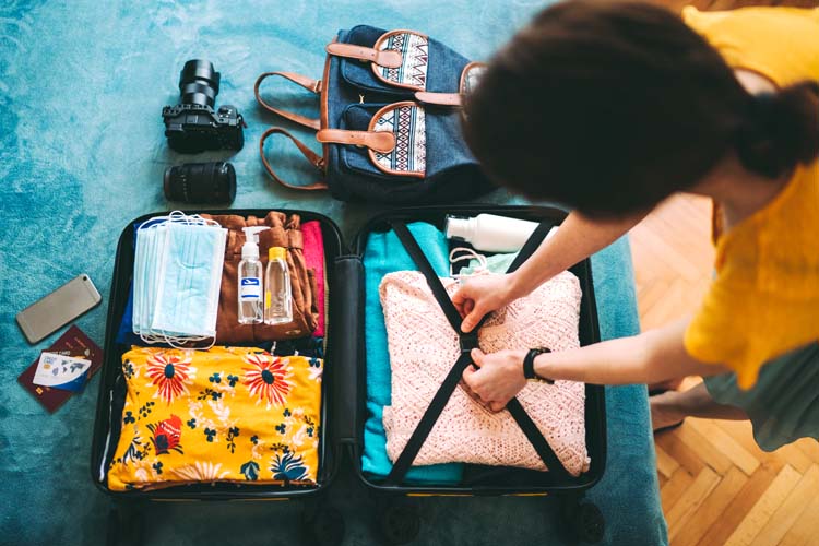 A woman is preparing her suitcase for travel during the COVID-19 pandemic.