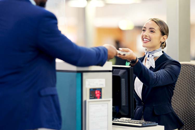 Passenger assistant helping traveller with checkin at terminal counter.