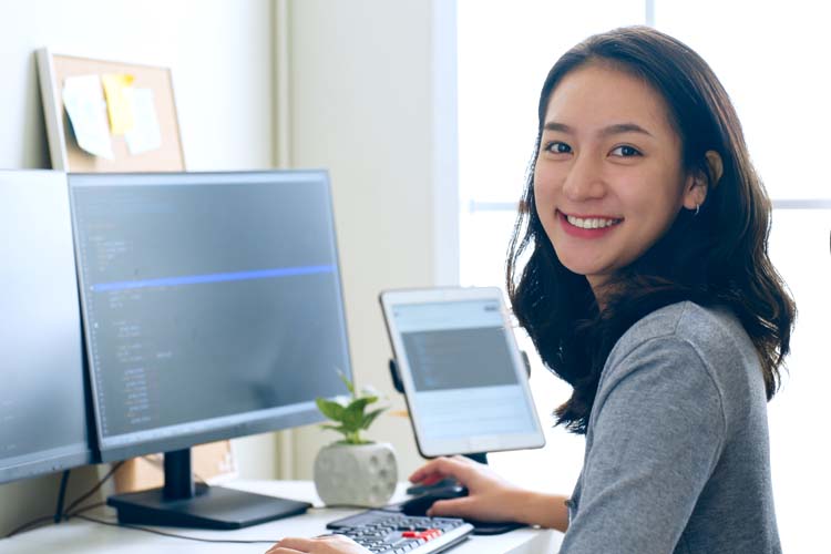 Asian woman data scientist looks at the camera and working at the office.