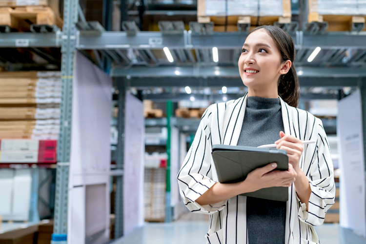 A woman using digital tablet checking amount of stock product inventory.
