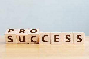 A wooden cube flips through the process to success on a wooden table.