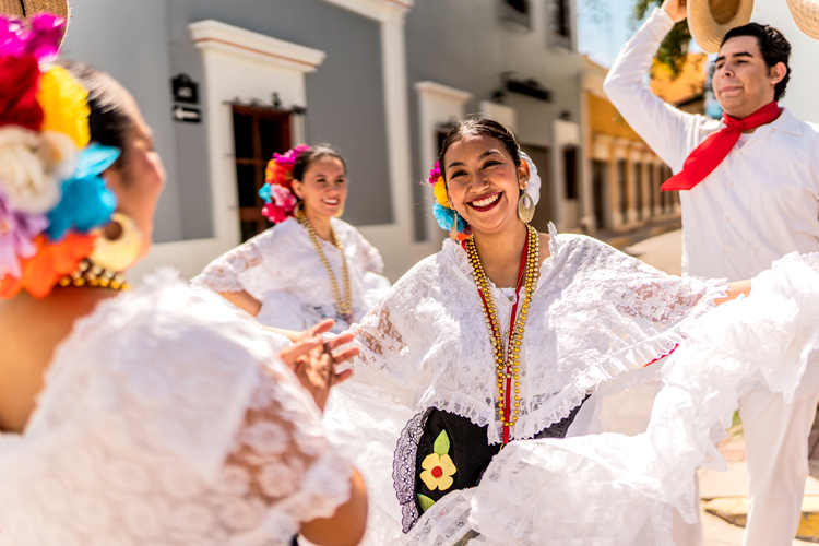 Young woman dancing with traditional Mexican clothing outdoors.
