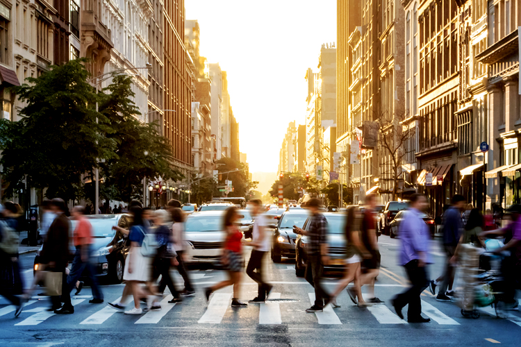 Crowds of people walking across a busy crosswalk in New York City.