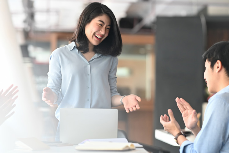 Team applauds boss during a meeting in modern conference room.