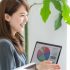 Asian woman presenting financial data on a laptop, smiling, in office setting.