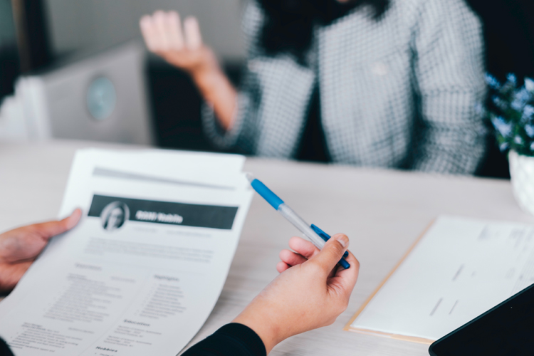 A person holds a resume while discussing with another individual in an interview.