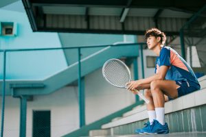 Asian Chinese professional male tennis player sitting in stadium tennis court in the morning.