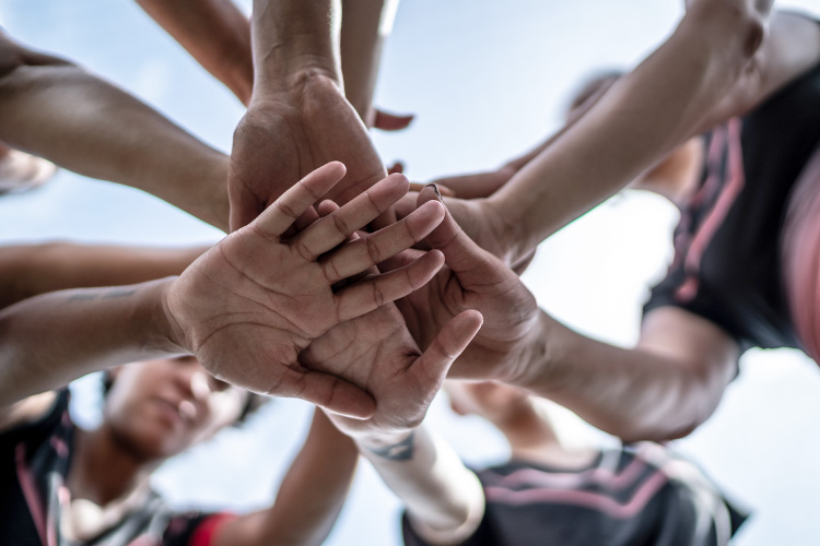 Close-up of female soccer team stacking hands in the field.