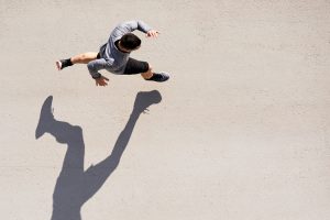An aerial view of a runner in motion, casting a long shadow on the ground.