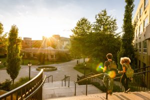 Two university students walk down campus stairs.