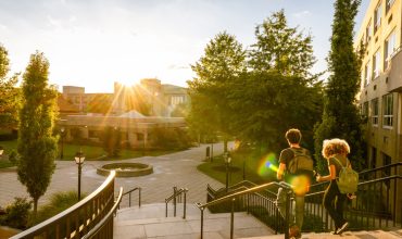 Two university students walk down campus stairs.