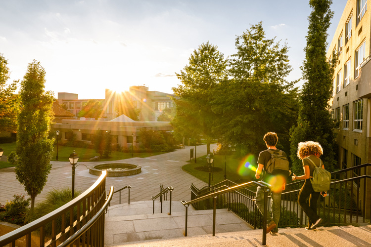 Two university students walk down campus stairs.