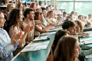 Cheerful college students applauding on a class at lecture hall.