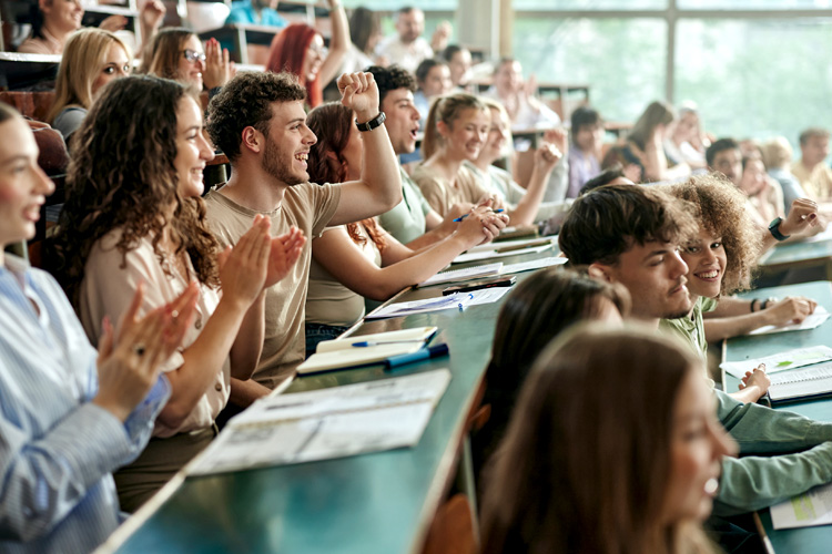 Cheerful college students applauding on a class at lecture hall.