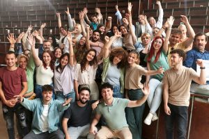 Crowd of happy students celebrating the end of school year in amphitheater.