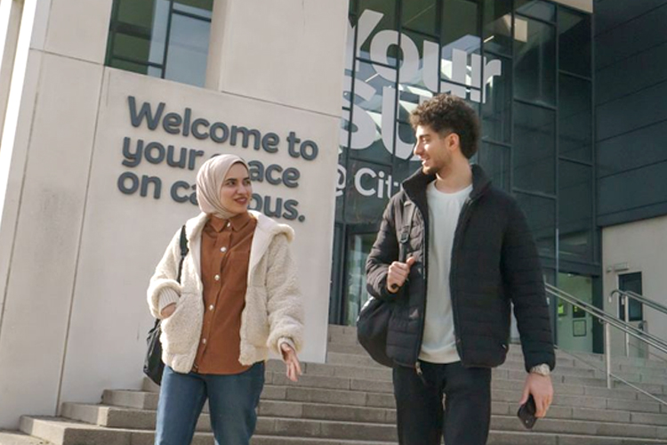 Two students walking together outside the Your SU building on campus.